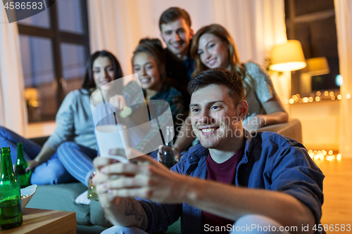 Image of friends with smartphone and drinks at night home