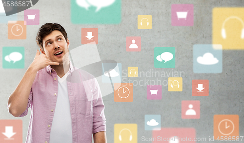 Image of man showing phone call gesture over app icons