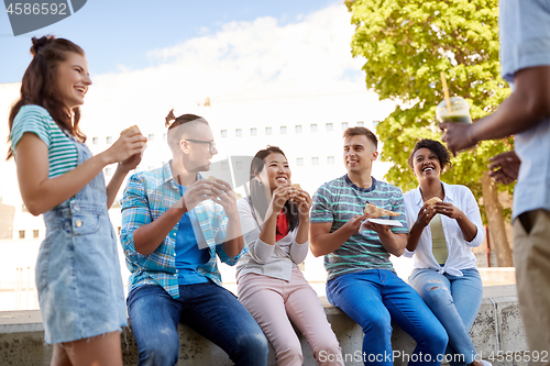 Image of friends eating sandwiches or burgers in park