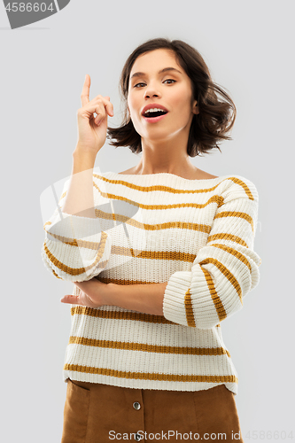 Image of woman in striped pullover pointing her finger up