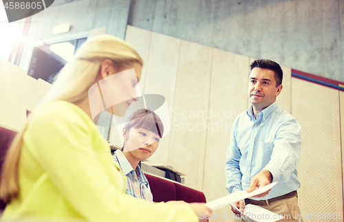 Image of teacher giving exam tests to students at lecture