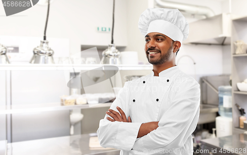 Image of smiling indian chef at restaurant kitchen