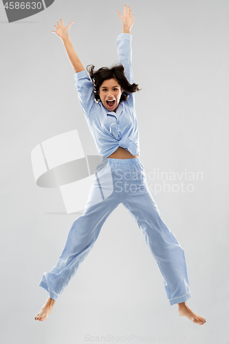 Image of happy woman in blue pajama jumping high