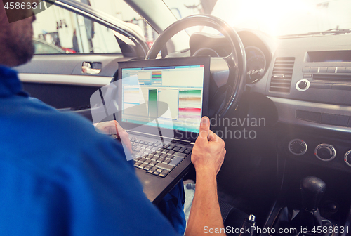 Image of mechanic man with laptop making car diagnostic