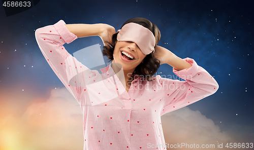 Image of happy young woman in pajama and eye sleeping mask