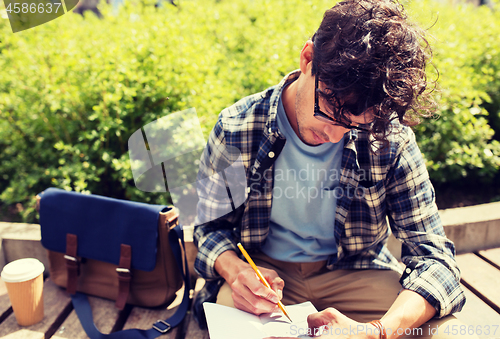 Image of man with notebook or diary writing on city street