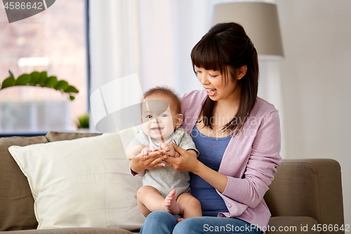 Image of happy young asian mother with little baby at home