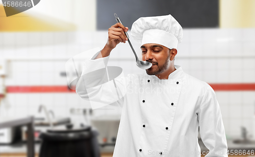 Image of happy indian chef tasting food by ladle at kitchen