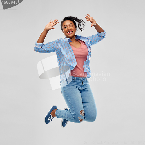 Image of happy african american woman jumping high