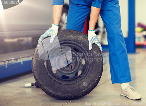 Image of mechanic with wheel tire at car workshop