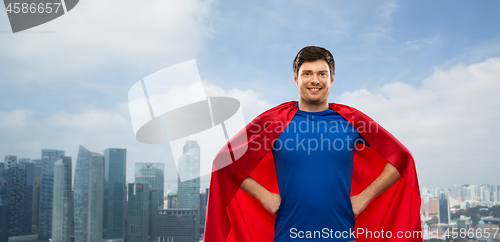 Image of man in red superhero cape over singapore city