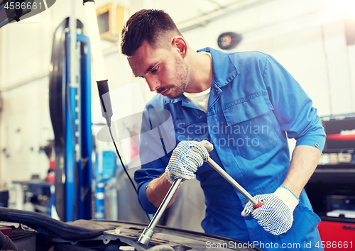 Image of mechanic man with wrench repairing car at workshop