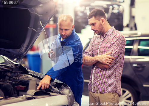 Image of auto mechanic with clipboard and man at car shop