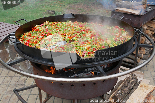 Image of A lot of various sliced vegetables are fried in big steel pan