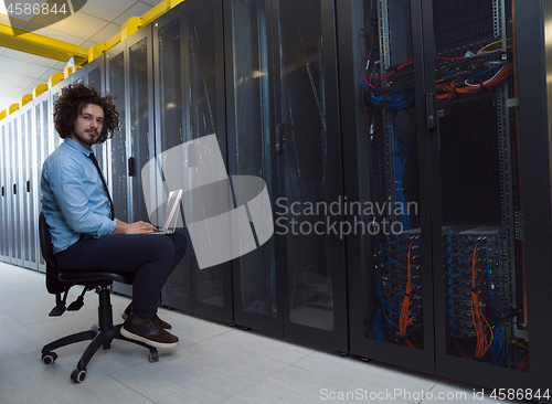 Image of engineer working on a laptop in server room