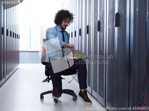 Image of engineer working on a laptop in server room