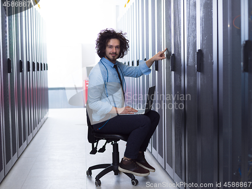 Image of engineer working on a laptop in server room