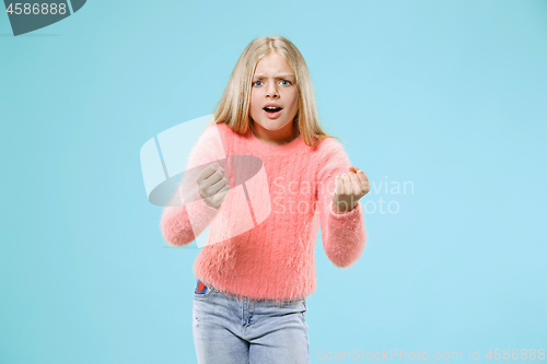 Image of Portrait of angry teen girl on a blue studio background