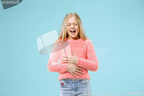 Image of The happy teen girl standing and smiling against blue background.