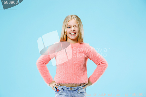 Image of The happy teen girl standing and smiling against blue background.