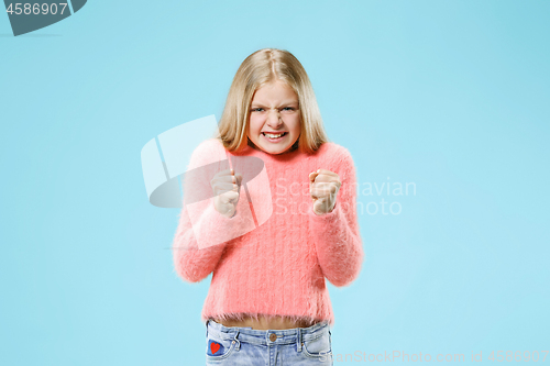 Image of Portrait of angry teen girl on a blue studio background