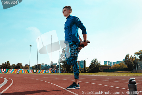 Image of Man runner stretching legs preparing for run training on stadium tracks doing warm-up