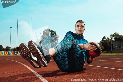 Image of Man runner stretching legs preparing for run training on stadium tracks doing warm-up