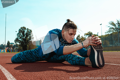 Image of Man runner stretching legs preparing for run training on stadium tracks doing warm-up