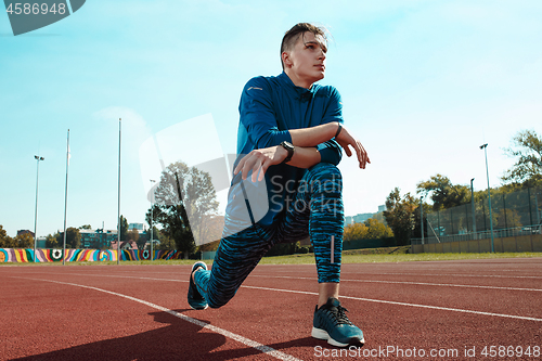 Image of Man runner stretching legs preparing for run training on stadium tracks doing warm-up