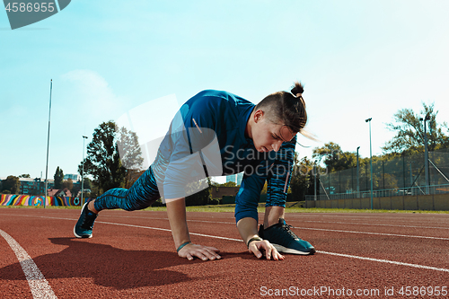 Image of Man runner stretching legs preparing for run training on stadium tracks doing warm-up