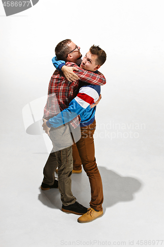 Image of Two friends in casual colorful wear standing and laughing together.