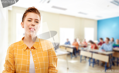 Image of red haired student girl showing tongue at school