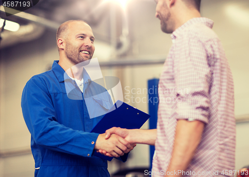 Image of auto mechanic and man shaking hands at car shop