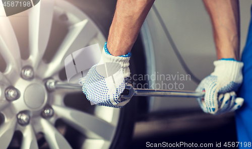 Image of mechanic with screwdriver changing car tire