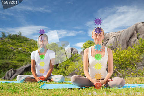 Image of couple doing yoga in lotus pose with seven chakras