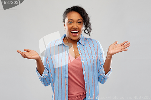 Image of surprised african american woman shrugging