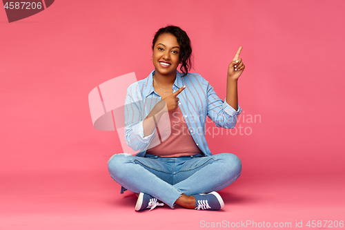 Image of happy african american woman pointing fingers up