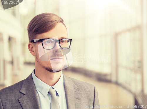 Image of young businessman in suit and glasses at office