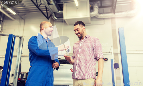 Image of auto mechanic giving key to man at car shop