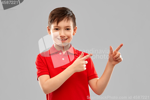 Image of happy boy in red t-shirt pointing fingers aside