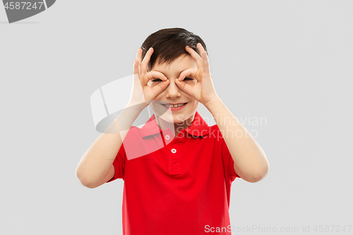 Image of boy in red t-shirt looking through finger glasses