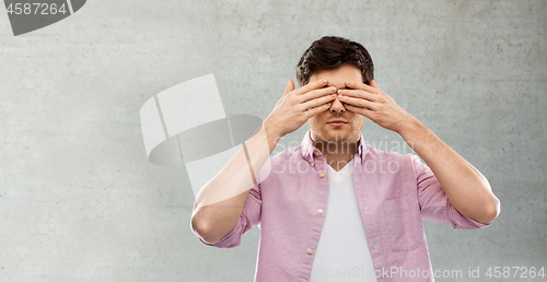 Image of man closing his eyes by hands over concrete wall