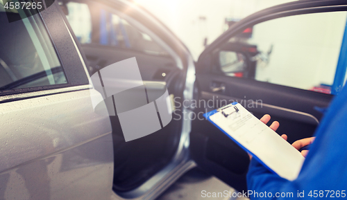 Image of auto mechanic man with clipboard at car workshop