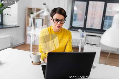 Image of businesswoman with laptop and coffee at office