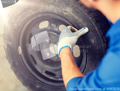 Image of mechanic with wheel tire at car workshop