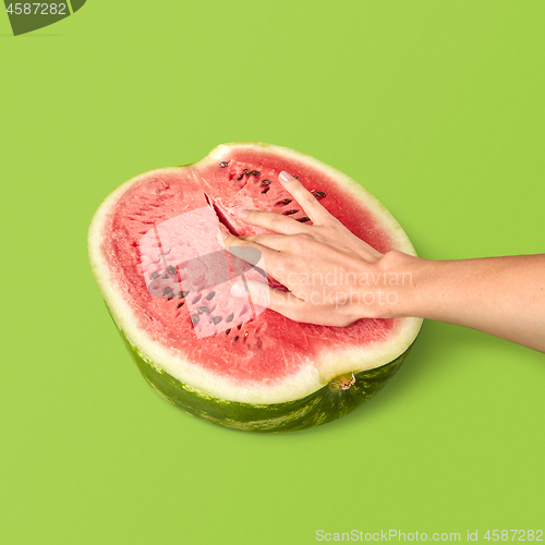 Image of Half of ripe organic watermelon with woman\'s fingers inside.