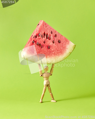 Image of Fresh ripe peace of watermelon in the hands of wooden mannequin model.