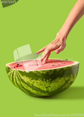 Image of Woman\'s hand touches ripe fresh organic watermelon puree.