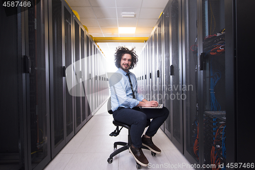 Image of engineer working on a laptop in server room