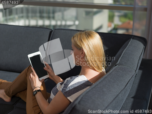 Image of young woman on sofa at home surfing web